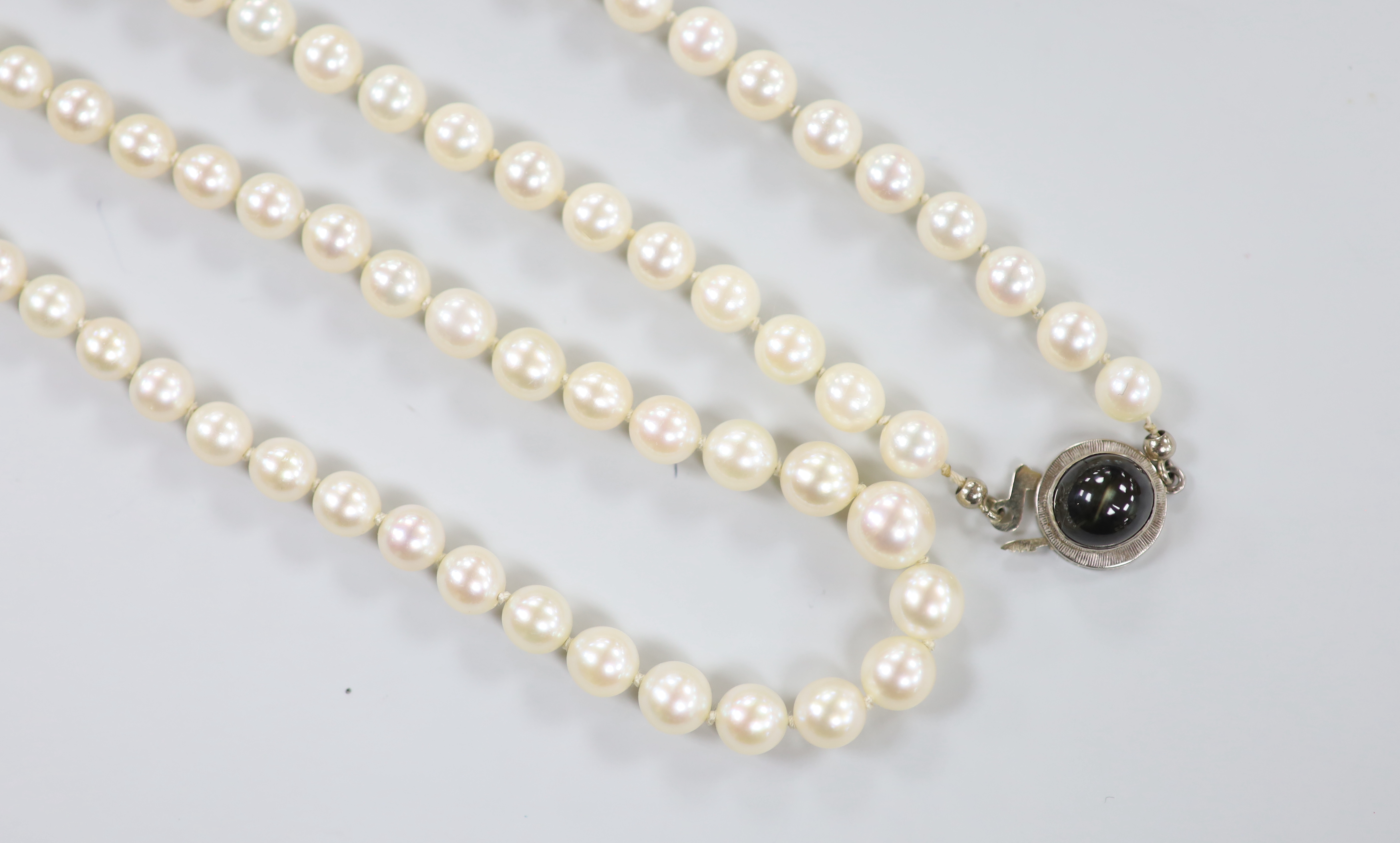 Two modern single strand cultured pearl necklaces, both with 750 white metal clasps, one with star sapphire, longest 62cm.